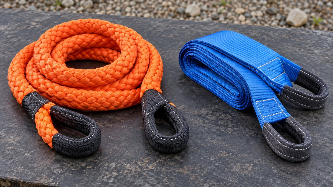 An orange braided kinetic recovery rope and a blue flat tow strap are displayed side by side on a charcoal surface.